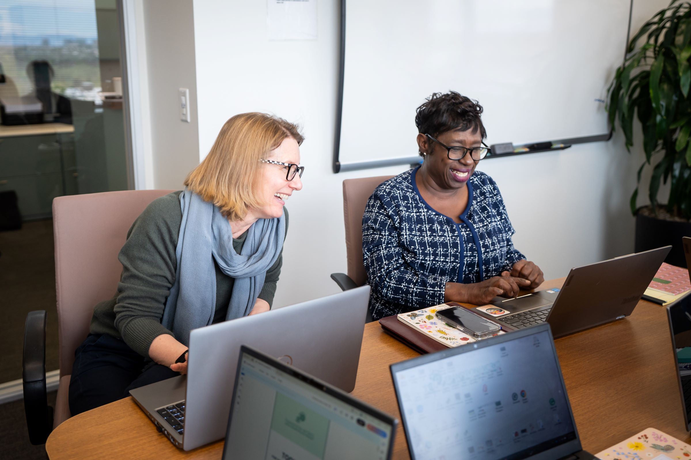 Two women working in an office, laughing.